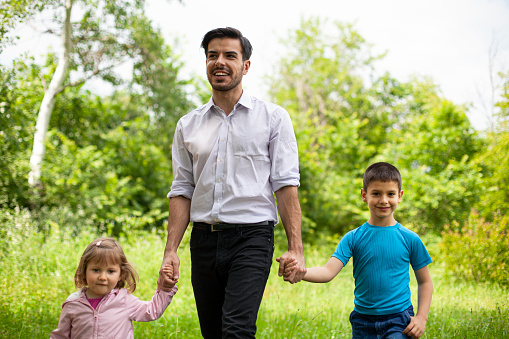 Father And Two Children Walking Through Woods at Park