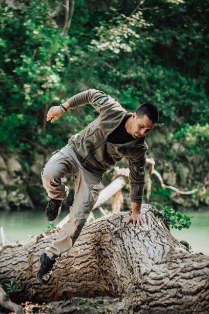 istock Man in a full military uniform leaps over a large tree trunk, executing a daring physical feat 1597043154