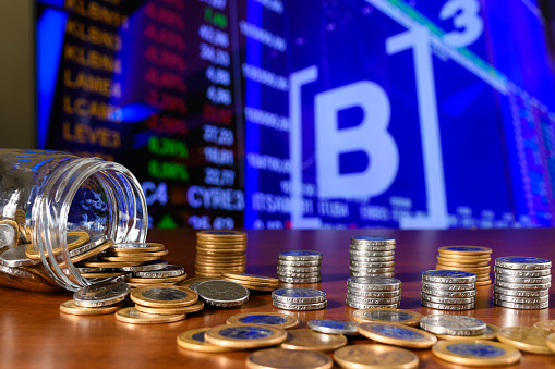 Coins in a glass jar on the background of the stock exchange