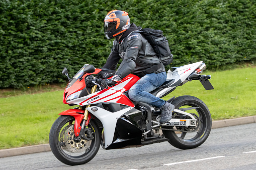 Whittlebury,Northants.,UK - Aug 6th 2023. 2014 red Honda CBR 600 RR-C motorcycle travelling through an English village.