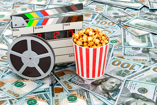 Clapperboard, film reel and popcorn on the dollars background, 3D rendering