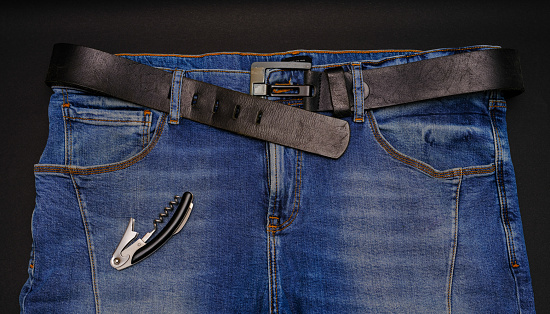 jeans with a belt and a corkscrew on a black background