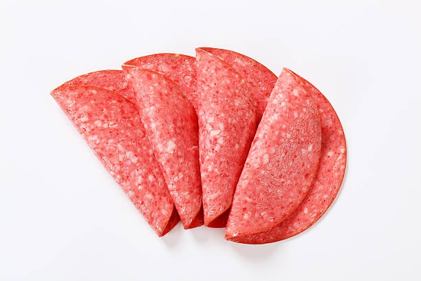 slices of a salami four folded thin slices of a red salami on a white background sliced salami stock pictures, royalty-free photos & images