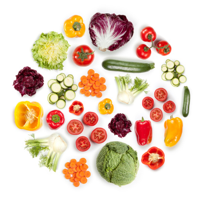 Healthy vegetarian food and organic vegetables, with fruits, greens, and produce. Arranged in a round circular shape on a white background. Cauliflower, zucchini, tomatoes, carrots, peppers.