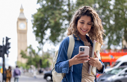 Happy exchange student using her cell phone while walking around London