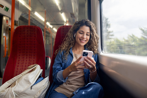 Mujer feliz viajando en un tren y revisando su teléfono celular photo