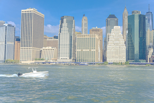 Skyline of Manhattan, New York. Downtown financial district on a clear sky day. Boat passing by the Hudson River.