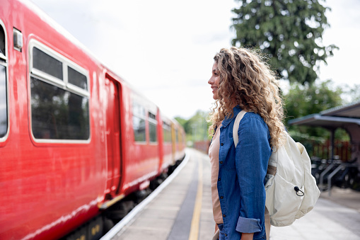 Happy woman at the station platform waiting for her train - public transportation concepts