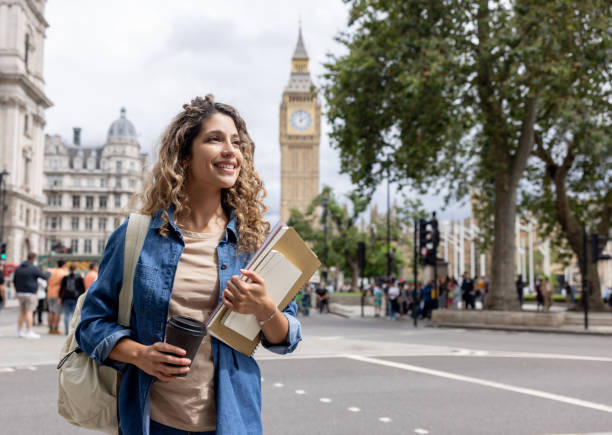 Exchange student walking outdoors in London and drinking coffee Portrait of a happy exchange student walking outdoors in London and drinking coffee on-the-go england stock pictures, royalty-free photos & images