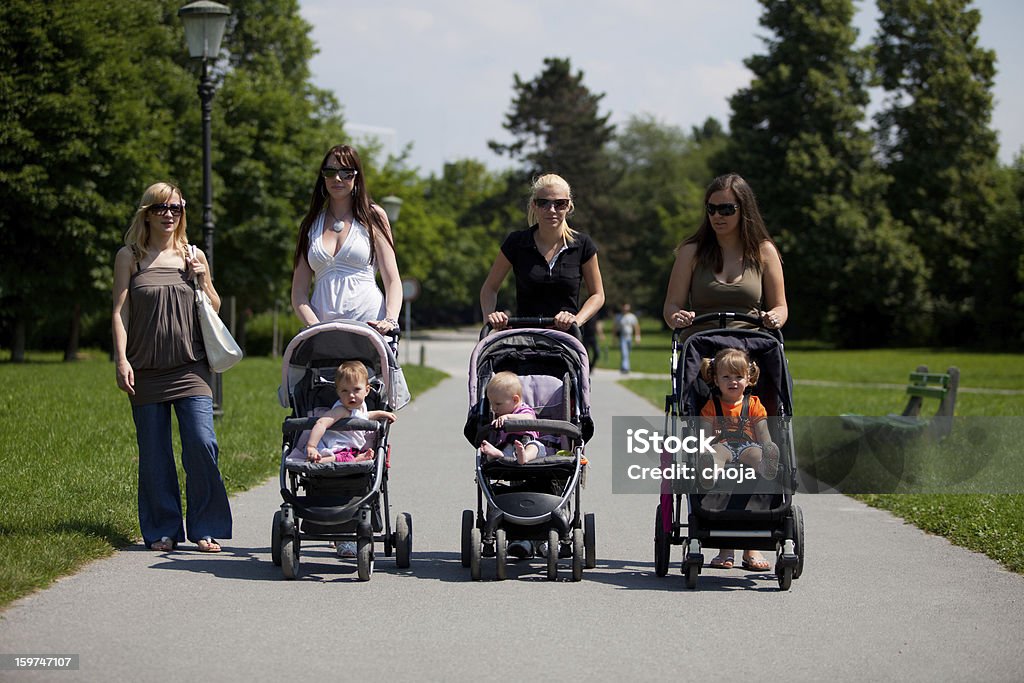 Jovens mães em um parque caminhada seus bebês - Foto de stock de 20 Anos royalty-free