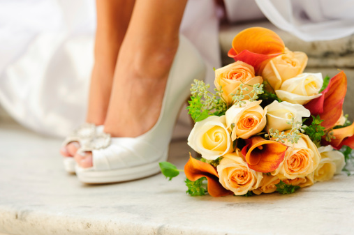 Bride sitting on steps (only calves and feet shown) next to bouquet.