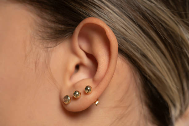 istock Female ear with three earrings 1597482569