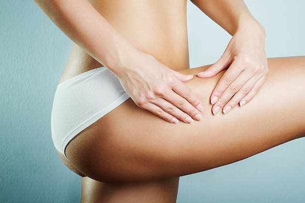 A closeup of a woman's midsection, pinching thigh cellulite  stock photo