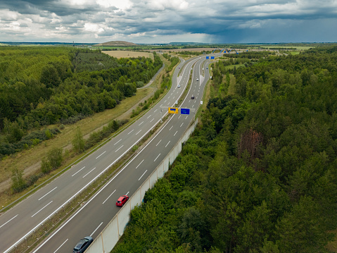 Aerial view of a variety of vehicles. Lifestyle photography from the air. Cars and other vehicle. Picture of road outdoors. Top View of Road Intersection. Multiple-lane highway with trucks in rural areas.