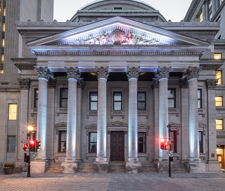 Montreal, Quebec, Canada - July 29, 2023:  The Bank of Montreal building in historic Old Montreal.  It sits on the perimeter of Place D'Armes Square.  It is the legal head office of the Bank of Montreal.  This location includes a museum as an homage to the bank's beginnings in 1817.