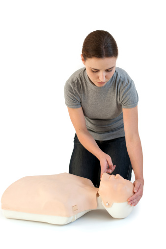 Girl performing first aid on a cpr dummy - pull up the chin.