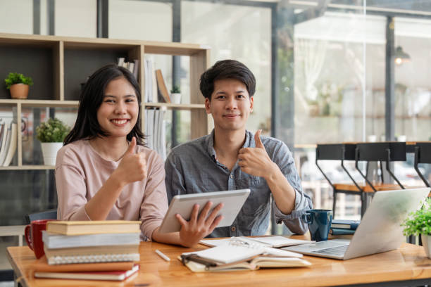 istock Happy smiling students looking at camera while preparing for exams by reading books at college campus concept of knowledge, education and competition 1597627587