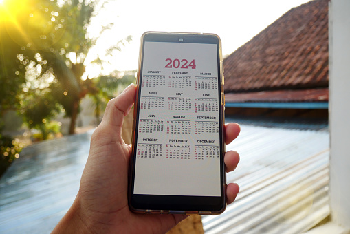 Smartphone on screen with calendar for 2024 in male hands. Android phone with calendar for 2024 on screen.