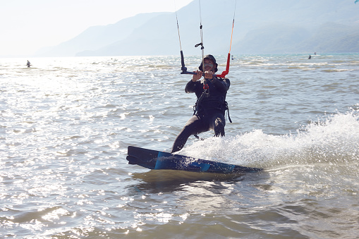 A young woman kitesurfer rides the waves doing a trick. Marine sports. kitesurfing.