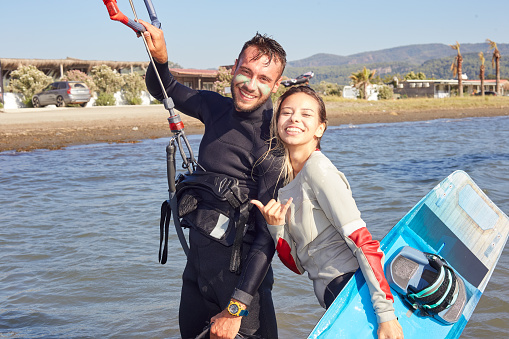 Smiling young kitesurf instructor training on the shore with her student