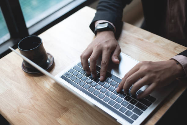 istock Businessman working on laptop computer with digital tablet on wooden table at modern office. Business man hands typing on laptop keyboard, online working 1597658828