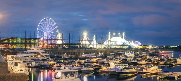 Montreal, Quebec, Canada - July 29, 2023:  A Ferris Wheel overlooking the Old Port area of Old Montreal commenced operations in 2017 and has been a major tourist draw since that time.  It is the most visible beacon in the Old Port amongst the many tourist attractions there.