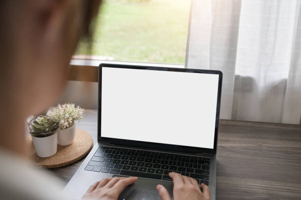 istock Woman hands typing on the laptop with empty blank white screen mockup. Computer is laying on the table. Person working from home concept. Copy space area for text 1597665629