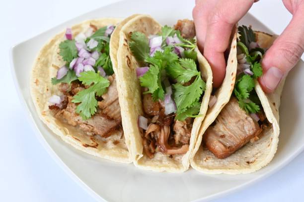 istock Hand holding a pork carnitas tacos. 1597684034