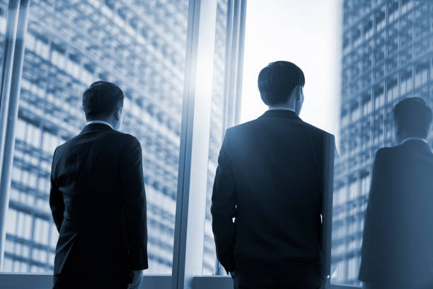 istock two asian businesspeople talking chatting standing by the window talking chatting in office 1597731017