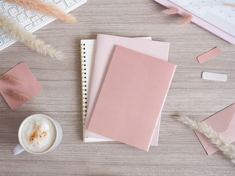 Flat lay top view with pink and beige accessories arranged on a wooden desk, cute woman's workspace, PC desk image