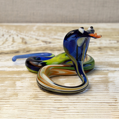 Figurine of snake from glass on rough wooden background front view