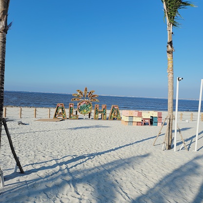 Photo of Aloha Beach a tourist spot on Pantai Indah Kapuk, Jakarta. There are coconut trees, white sand and sky views.