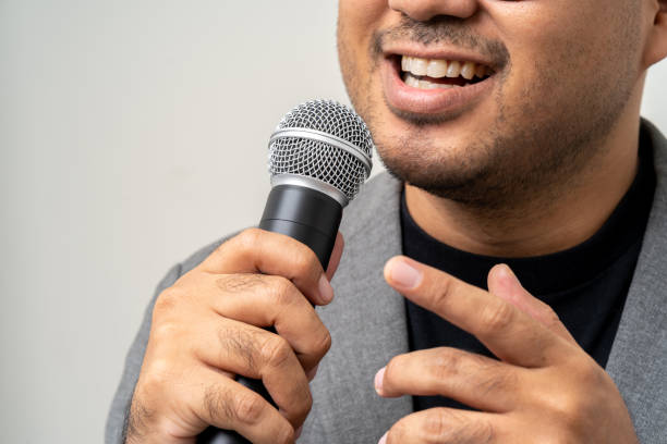 istock Close up businessman speaker hand holding High quality dynamic microphone and singing song or speaking talking with people on isolated white background. Male testing microphone voice for interview 1597789638
