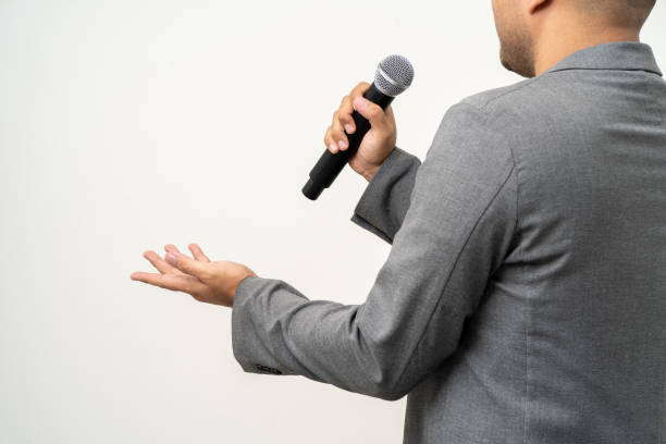 istock Close up businessman speaker hand holding High quality dynamic microphone and singing song or speaking talking with people on isolated white background. Male testing microphone voice for interview 1597789651