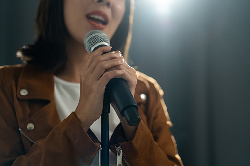 Close up woman hand holding High quality dynamic microphone and singing song or speaking talking with people on isolated white background. Woman testing microphone voice for interview