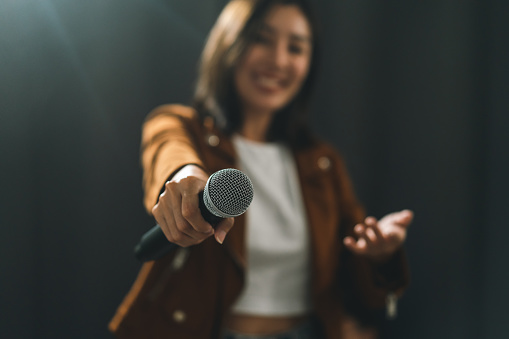 Close up woman hand holding High quality dynamic microphone and singing song or speaking talking with people on isolated white background. Woman testing microphone voice for interview