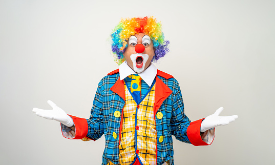 Mr Clown. Portrait of Funny shocked face comedian Clown man in colorful costume wearing wig standing posing smiling to camera. Happy expression amazed bozo in various pose on isolated background.