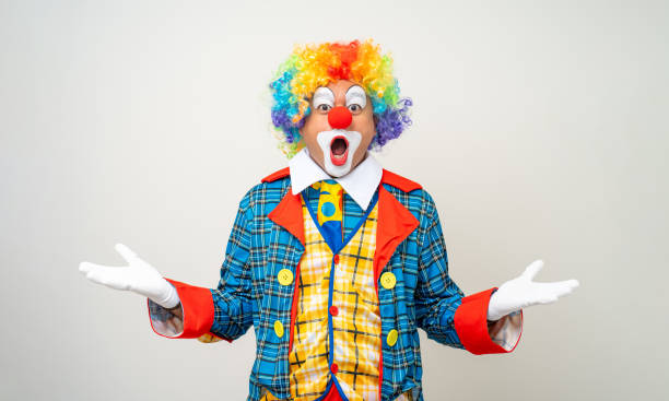 Mr Clown. Portrait of Funny shocked face comedian Clown man in colorful costume wearing wig standing posing smiling to camera. Happy expression amazed bozo in various pose on isolated background. Mr Clown. Portrait of Funny shocked face comedian Clown man in colorful costume wearing wig standing posing smiling to camera. Happy expression amazed bozo in various pose on isolated background. clown stock pictures, royalty-free photos & images