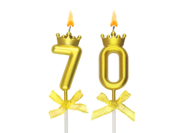 istock Gold birthday candles burning on white, number 70. 1597791179
