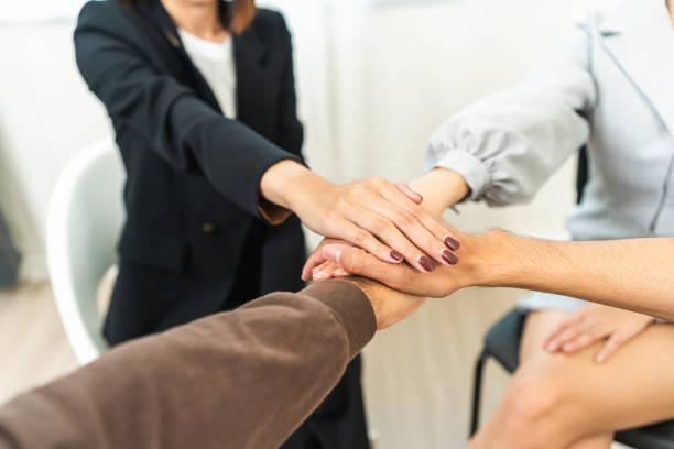 istock Multiethnic of young people putting their hands together in group therapy session. Support of counselor diverse people friend group help motivation making a stack of hands. 1597791279