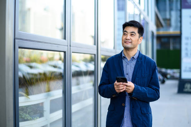 istock Asian middle-aged business man using digital tablet on city street 1597791479