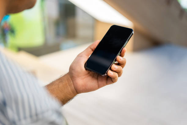 istock Young man holding using smartphone on urban city background. 1597800040