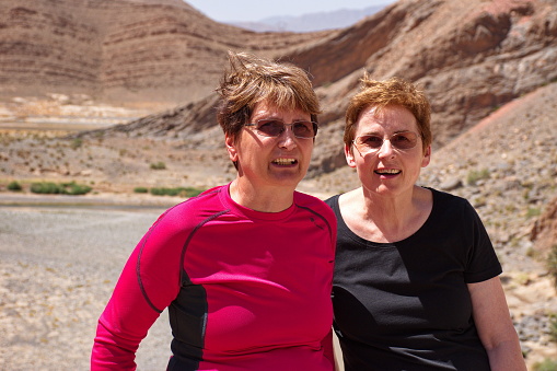Two senior women with arid landscape of Morocco in background