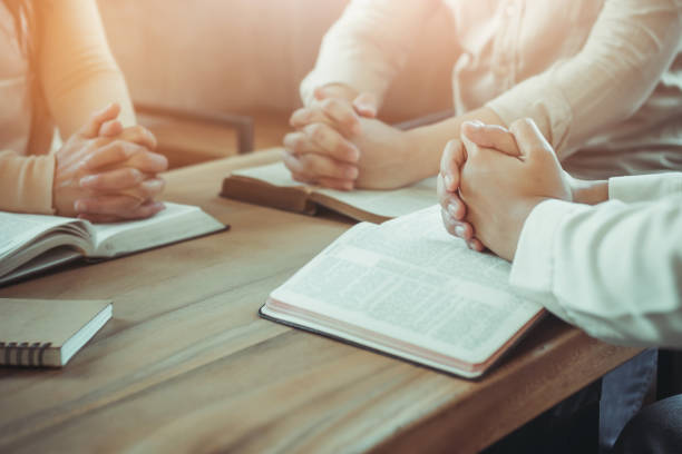 istock group of christian  praying while sitting around wooden table 1597824713