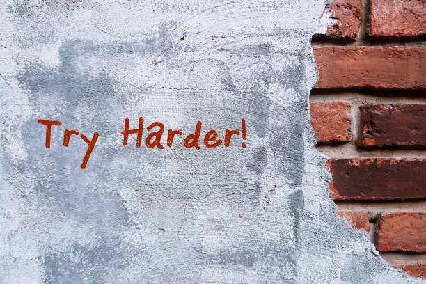 istock A grunge vintage brick wall and grey cement with hand written text TRY HARDER, concept of never give up and be persistent. 1597838355