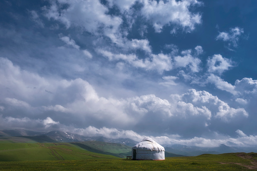 Traditional Kazakh yurt in the mountains against the background of cloudy sky in summer on a pasture