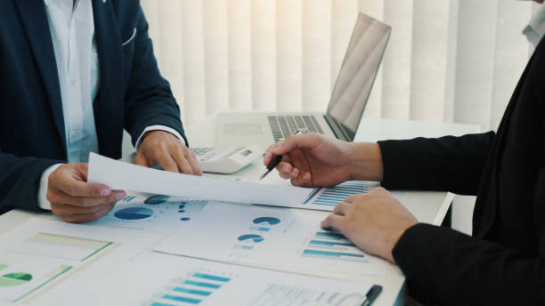 istock Two business partnership coworkers analysis cost work progress and gesturing with discussing a financial planning graph and company financial during a budget meeting in office room. 1597870821