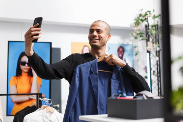 istock Man holding jacket hanger, taking selfie 1597895951