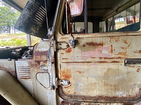 Horizontal still life of rustic + rusted old ute truck parked in farm shed with nature glimpse on rural country property Australia