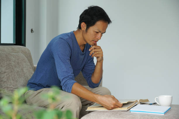 istock asian men reading a book in well-being at home. 1597966947